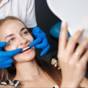 woman smiling and looking at mirror with dentist behind