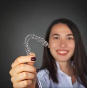 woman smiling at camera holding aligners