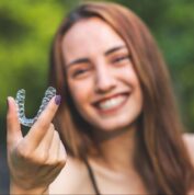 beautiful smiling turkish woman is holding an invisalign bracer with vibrant colours