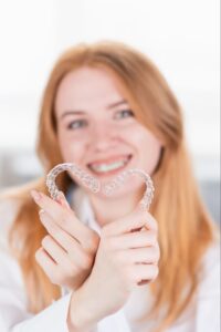 dental care smiling girl with red hair holding heart shaped aligner